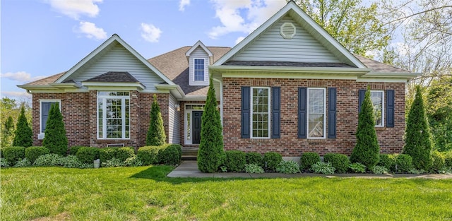 view of front of property featuring brick siding, a shingled roof, and a front yard