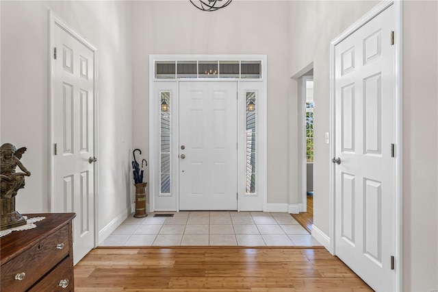 foyer entrance featuring light wood-type flooring, baseboards, and a high ceiling