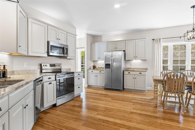 kitchen with an inviting chandelier, plenty of natural light, stainless steel appliances, and light wood-style flooring