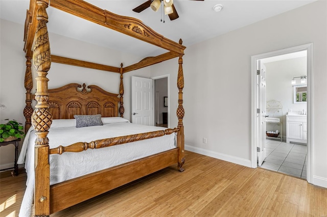 bedroom featuring baseboards, ceiling fan, ensuite bath, and wood finished floors