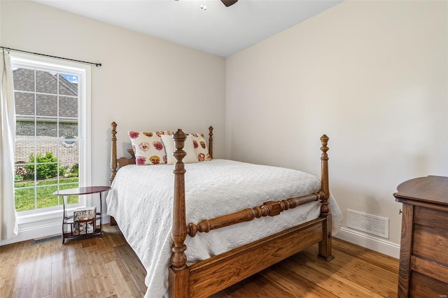 bedroom featuring visible vents, wood finished floors, and multiple windows