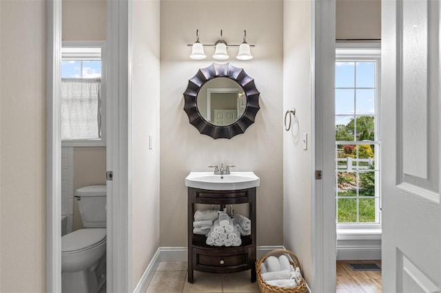bathroom featuring a sink, baseboards, toilet, and visible vents