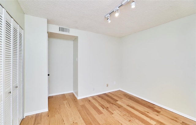 empty room with baseboards, visible vents, wood finished floors, and a textured ceiling