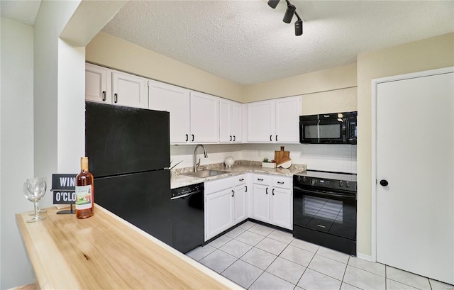 kitchen featuring light tile patterned floors, black appliances, a sink, and white cabinets