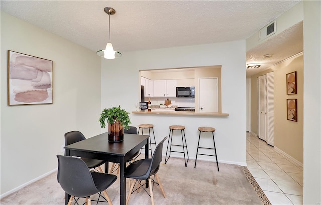 dining space with baseboards, visible vents, light tile patterned floors, and a textured ceiling