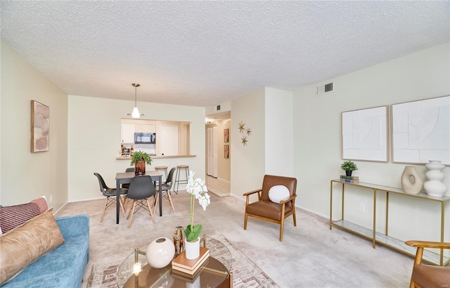 living area featuring a textured ceiling, visible vents, and light carpet