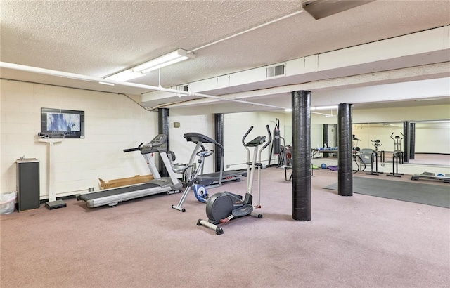 exercise room with visible vents, a textured ceiling, and concrete block wall
