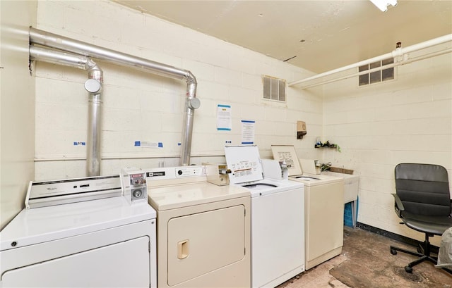 common laundry area featuring visible vents, washer and dryer, concrete block wall, and a sink