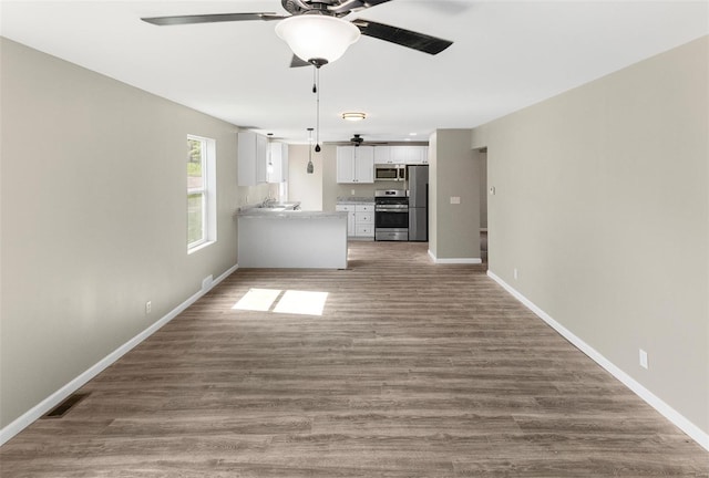 unfurnished living room with a ceiling fan, wood finished floors, and baseboards