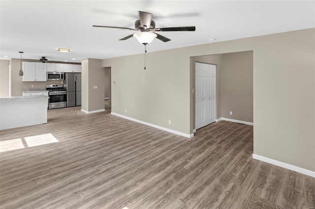 unfurnished living room with ceiling fan, light wood-style flooring, and baseboards
