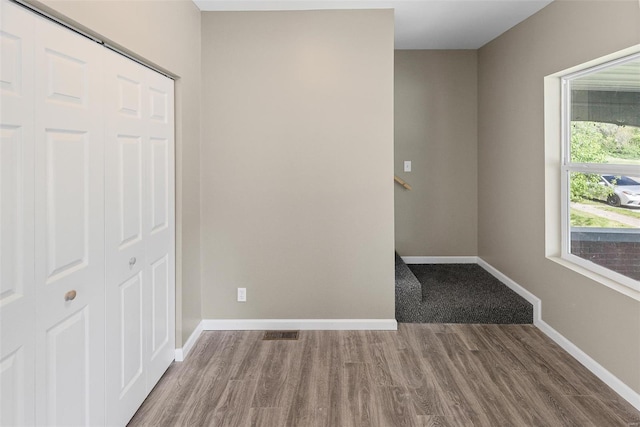 unfurnished room featuring visible vents, wood finished floors, and baseboards