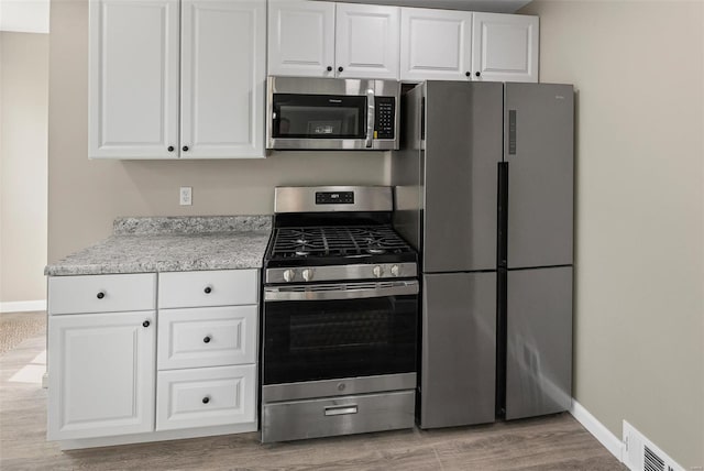 kitchen featuring white cabinetry, light wood-style flooring, appliances with stainless steel finishes, visible vents, and baseboards