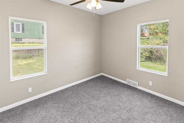 carpeted spare room with visible vents, a ceiling fan, and baseboards