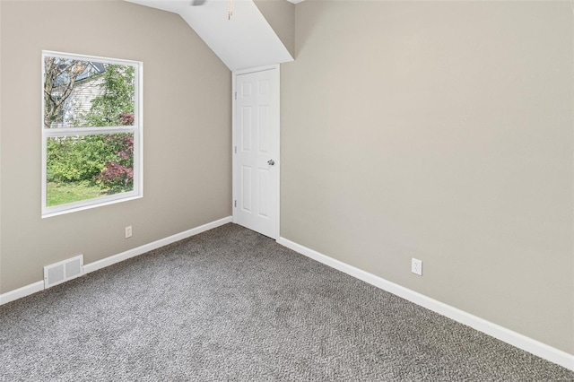 additional living space with baseboards, visible vents, dark carpet, a ceiling fan, and lofted ceiling