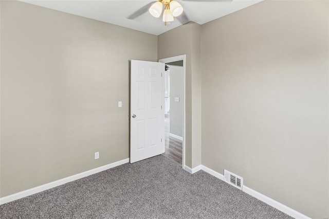 spare room featuring visible vents, dark colored carpet, a ceiling fan, and baseboards