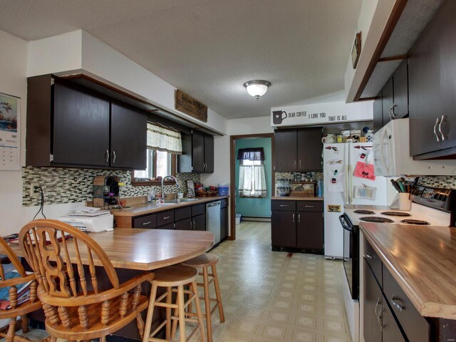 kitchen featuring light floors, dishwasher, a sink, decorative backsplash, and electric range