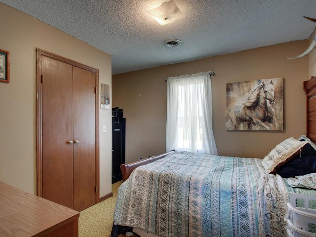 carpeted bedroom with a textured ceiling, visible vents, and a closet
