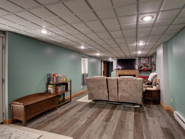 living area with wood finished floors, a tiled fireplace, baseboards, and baseboard heating
