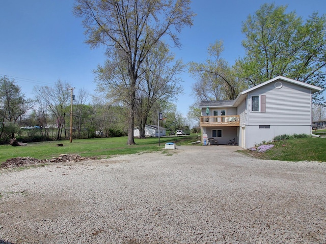exterior space with gravel driveway, a yard, and a deck
