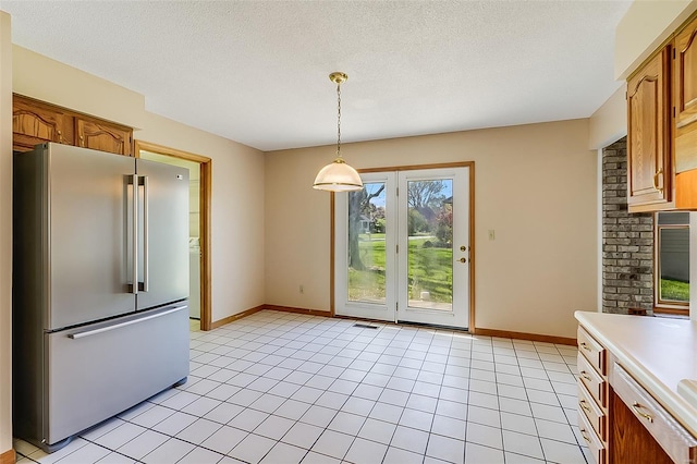 unfurnished dining area with light tile patterned flooring, baseboards, and a textured ceiling