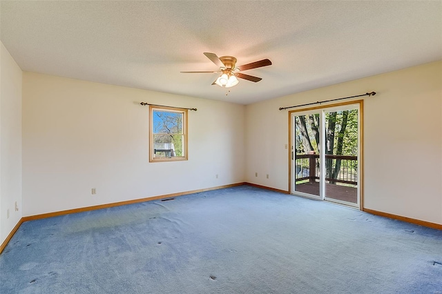 carpeted spare room with a healthy amount of sunlight, baseboards, a ceiling fan, and a textured ceiling