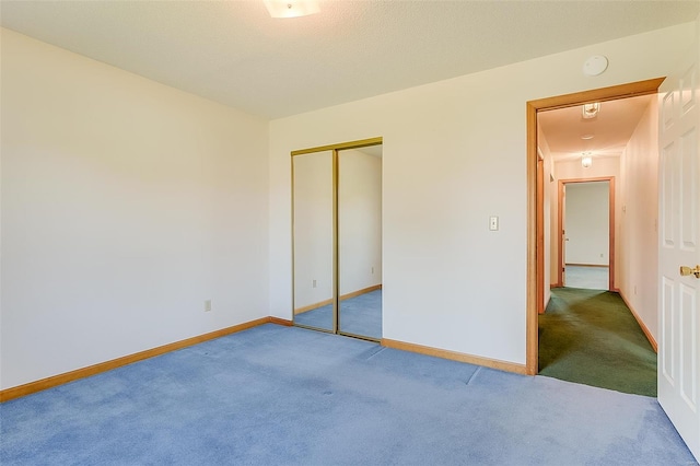 unfurnished bedroom featuring carpet floors, baseboards, and a closet