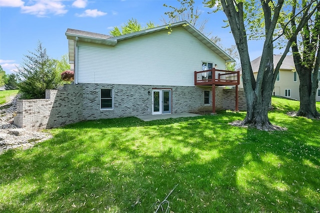 back of property with a yard, a wooden deck, and a patio area