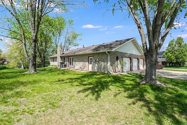view of side of home with driveway, a chimney, a garage, brick siding, and a yard