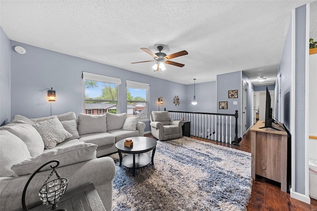 living room featuring a textured ceiling, ceiling fan, and dark wood-style floors