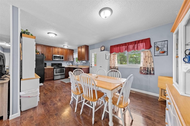 dining room featuring dark wood-style flooring, a textured ceiling, and baseboards