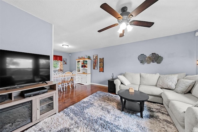 living area with baseboards, a ceiling fan, and wood finished floors