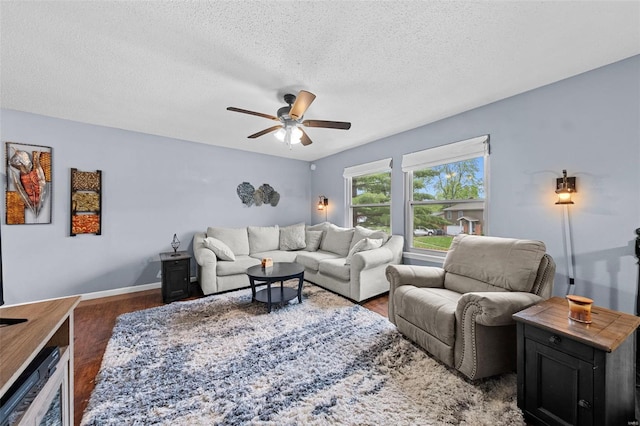 living room with a textured ceiling, baseboards, a ceiling fan, and wood finished floors