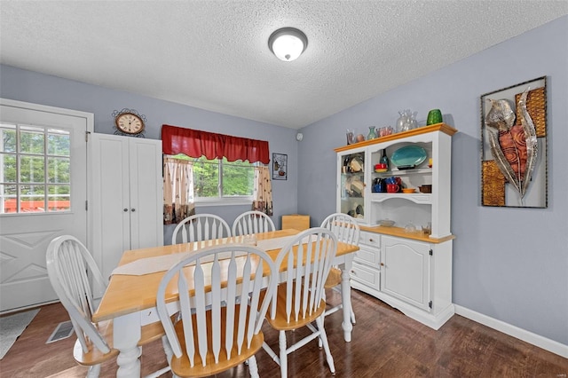 dining space with baseboards, a textured ceiling, and dark wood finished floors