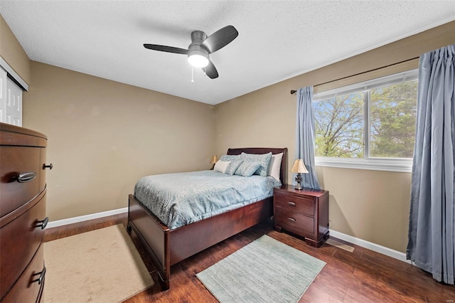 bedroom with baseboards, dark wood-style floors, a textured ceiling, and visible vents