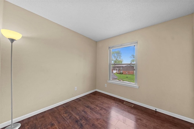 unfurnished room featuring visible vents, a textured ceiling, baseboards, and wood finished floors