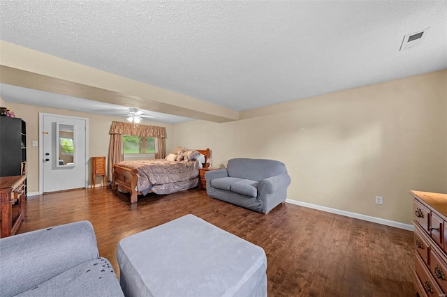 bedroom with baseboards, a textured ceiling, wood finished floors, and visible vents