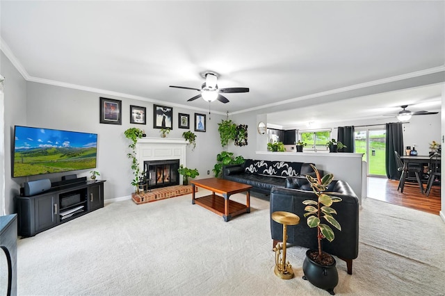 living area featuring a ceiling fan, baseboards, a fireplace, and crown molding