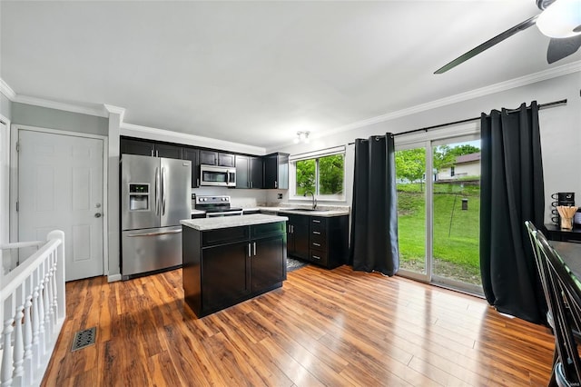 kitchen with ornamental molding, a center island, and appliances with stainless steel finishes