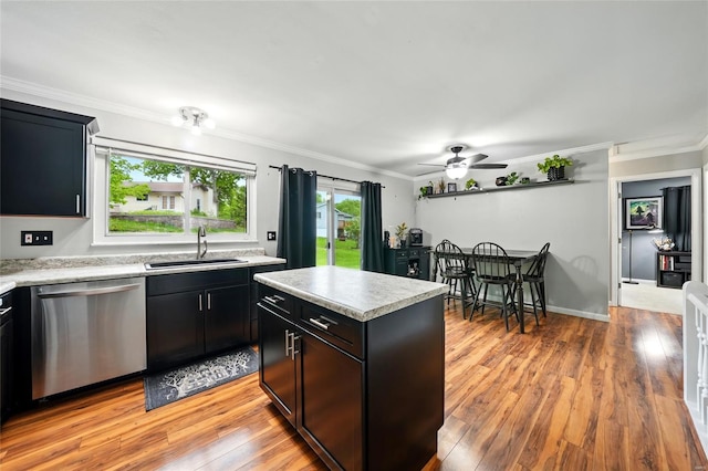 kitchen featuring light countertops, crown molding, stainless steel dishwasher, and a sink