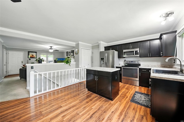kitchen with a sink, light countertops, a center island, dark cabinets, and appliances with stainless steel finishes