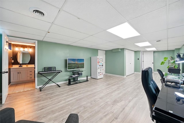 office space with a drop ceiling, wood finished floors, a sink, visible vents, and baseboards