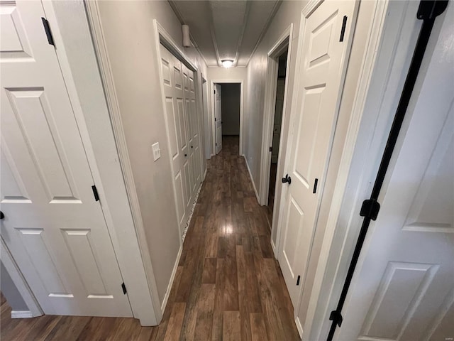 hallway featuring baseboards and dark wood-type flooring