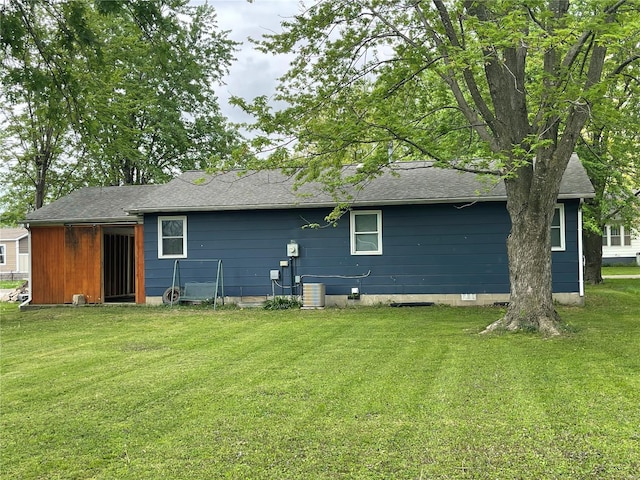 rear view of property featuring a shingled roof and a lawn
