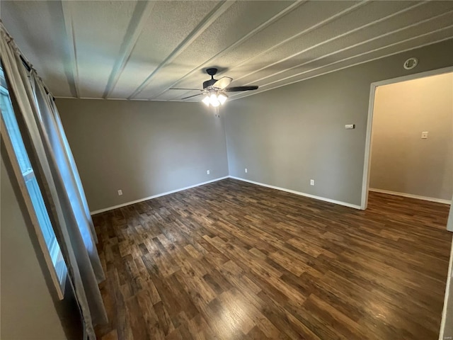 empty room with baseboards, ceiling fan, and dark wood-type flooring