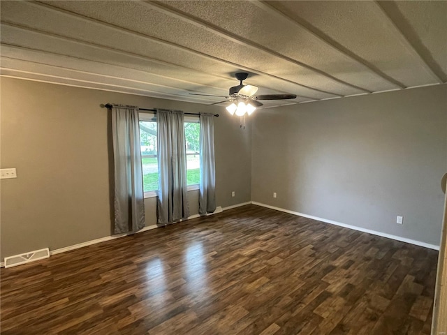 spare room featuring dark wood-style floors, visible vents, and baseboards