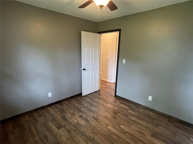 spare room featuring a ceiling fan, dark wood finished floors, and baseboards