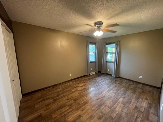 unfurnished bedroom featuring a textured ceiling, dark wood finished floors, and baseboards