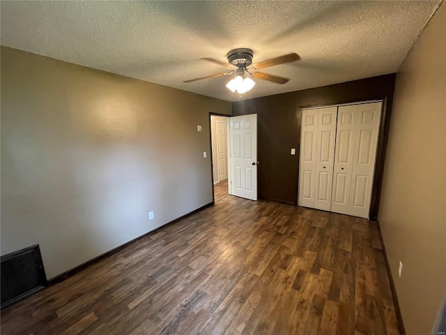 unfurnished bedroom with a textured ceiling, a closet, dark wood finished floors, and baseboards