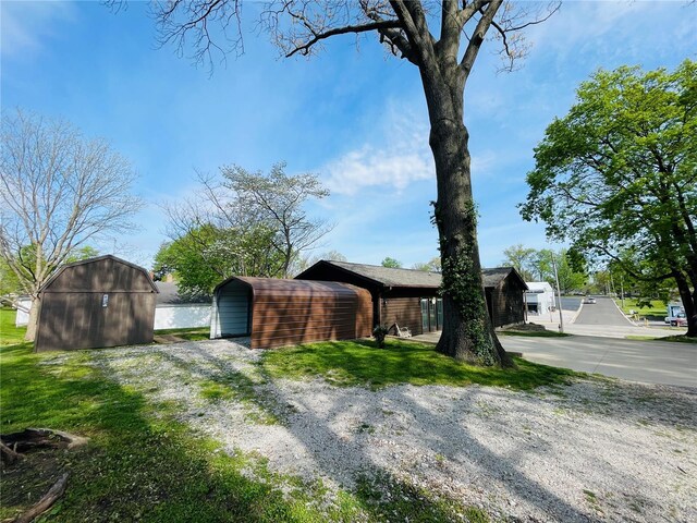 view of home's exterior featuring a storage shed, driveway, a carport, and an outdoor structure