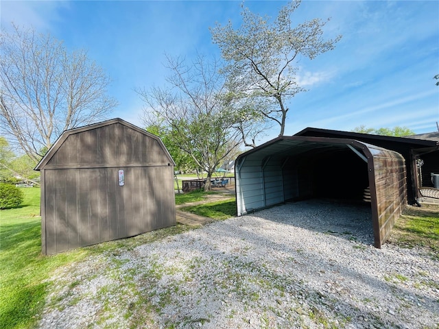 garage with gravel driveway, a shed, and a detached carport